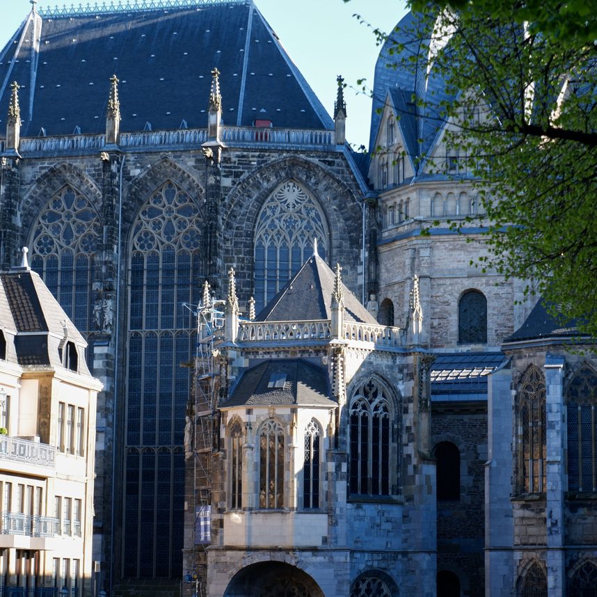 The tall Gothic windows and buttresses of the choir of Aachen Cathedral in sunshine