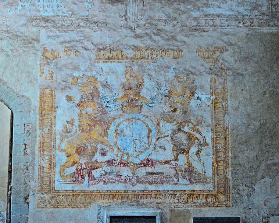 A large painted royal coat of arms, faded red, blue and gold, on a whitewashed wall at Dore Abbey
