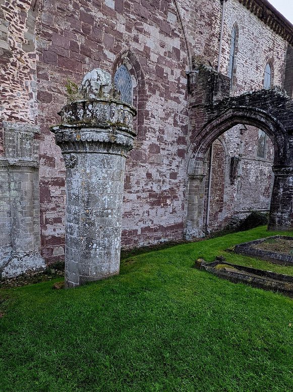 A ruined stone pier and arch standing in the grass west of Dore Abbey, the remains of the demolished nave