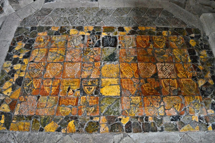 A patch of worn medieval floor tiles with yellow patterns on red at Dore Abbey