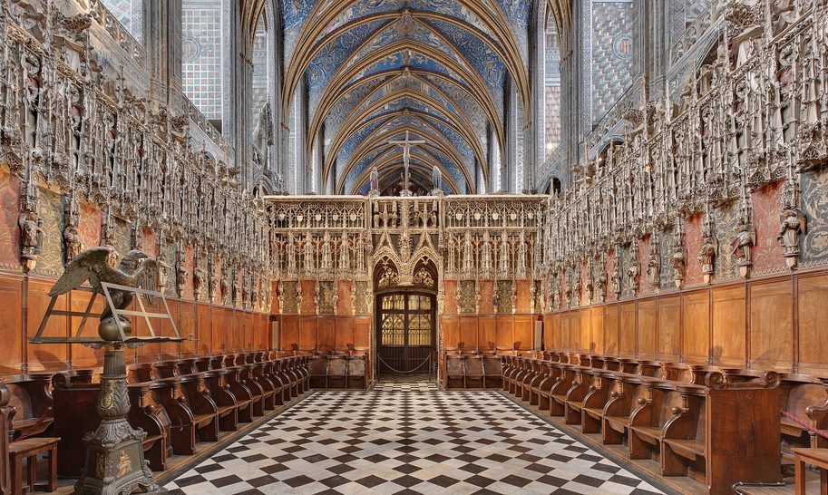 The canons' choir of Albi Cathedral, with carved wooden stalls under a stone screen of pinnacles and painted statues