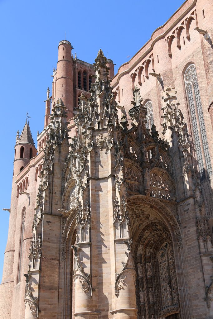 The white stone Flamboyant Gothic canopy of the south porch of Albi Cathedral against the red brick walls