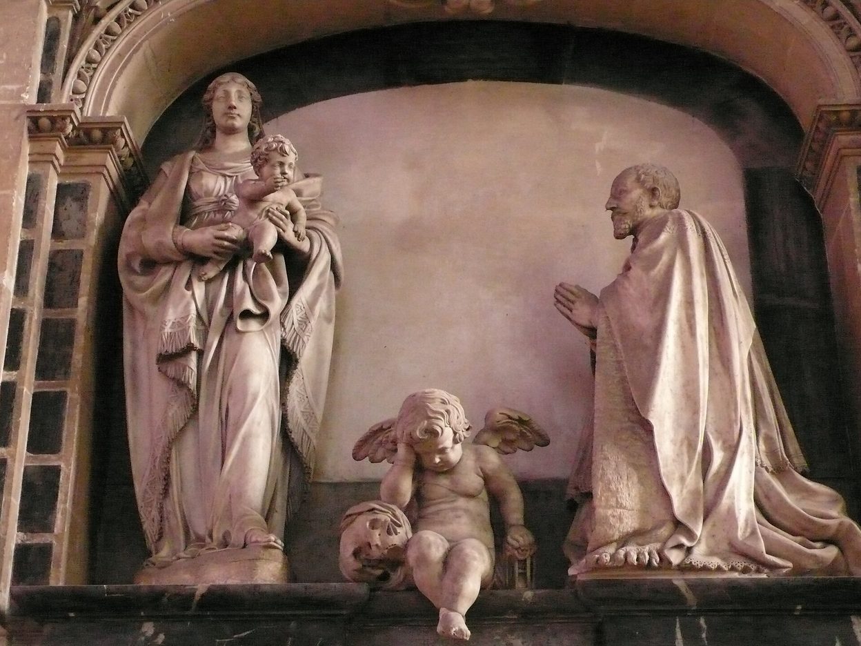 A marble funerary monument with the Virgin and Child, a kneeling canon and a small weeping angel seated between them