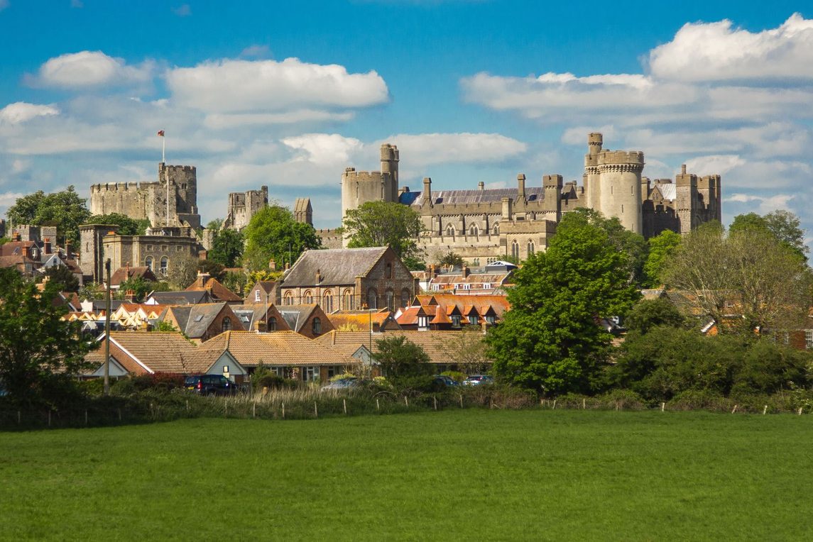 Arundel Castle and the roofs of the town on the hillside above green fields