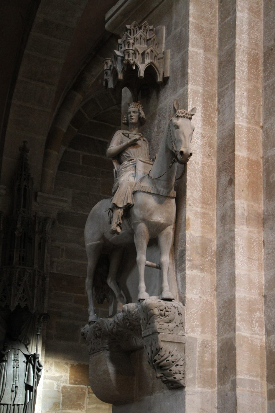 The Bamberg Horseman, a medieval stone statue of a crowned rider on a horse, standing on a pier in Bamberg Cathedral