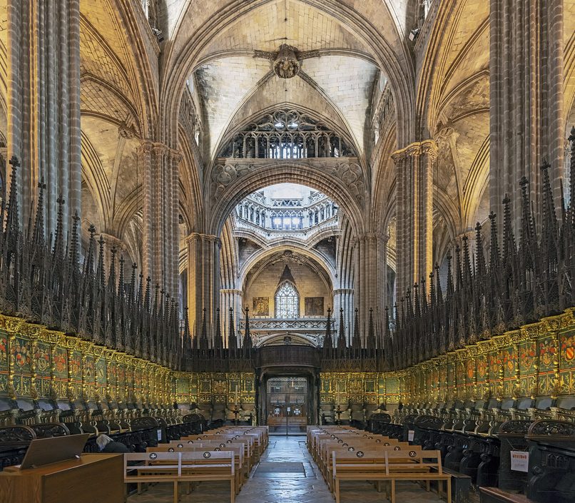The carved wooden choir stalls of Barcelona Cathedral with painted coats of arms above them