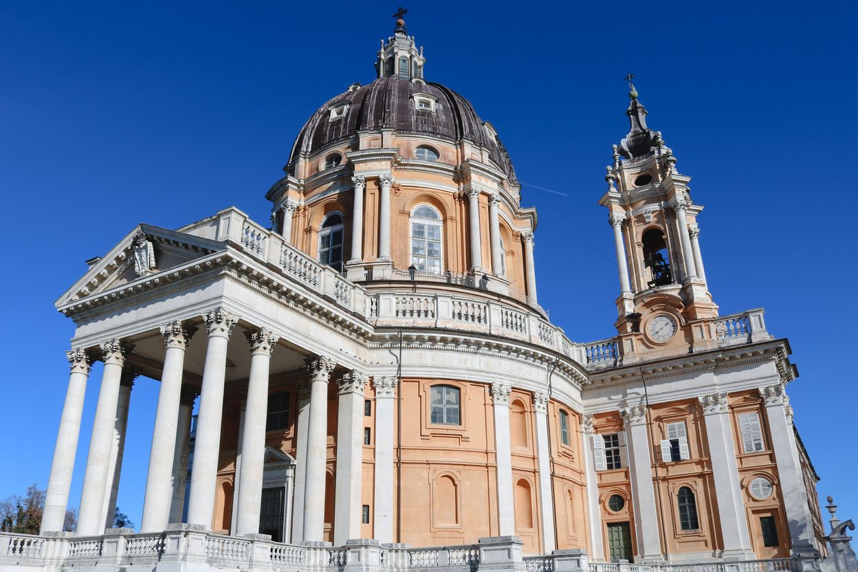 The Basilica of Superga, a Baroque church with a columned portico, a tall dome and twin bell towers, against a blue sky