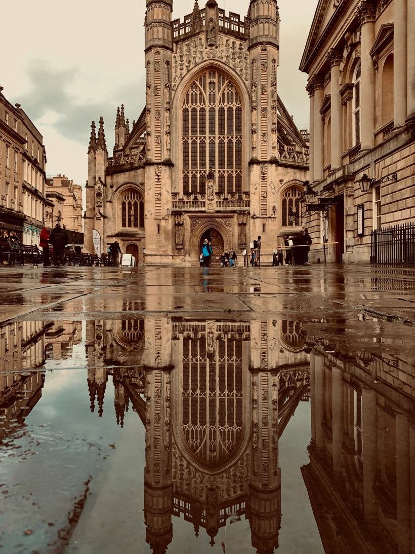 Bath Abbey reflected in a puddle on the pavement