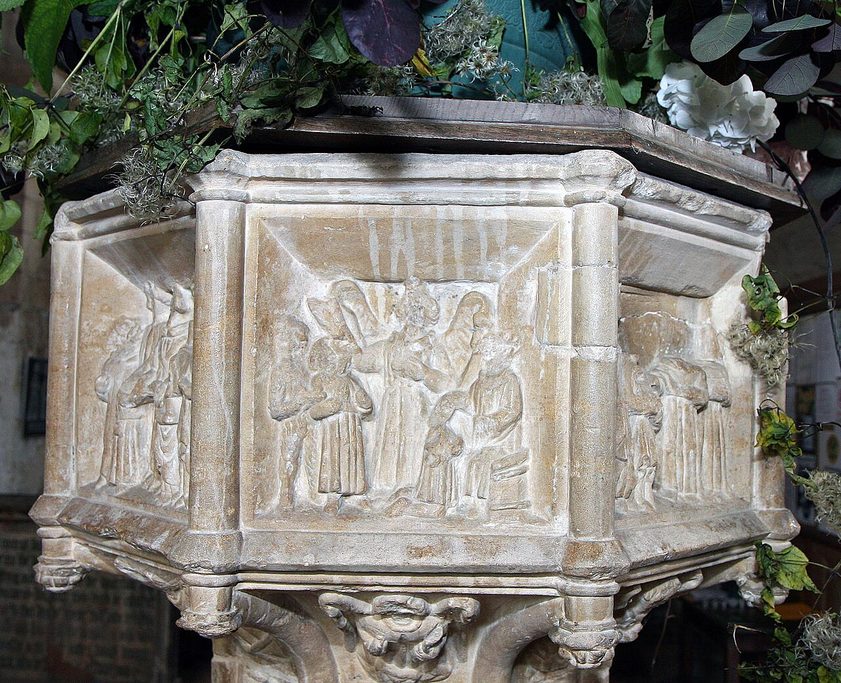 The octagonal stone Seven Sacrament font at Binham Priory, carved with worn figure scenes