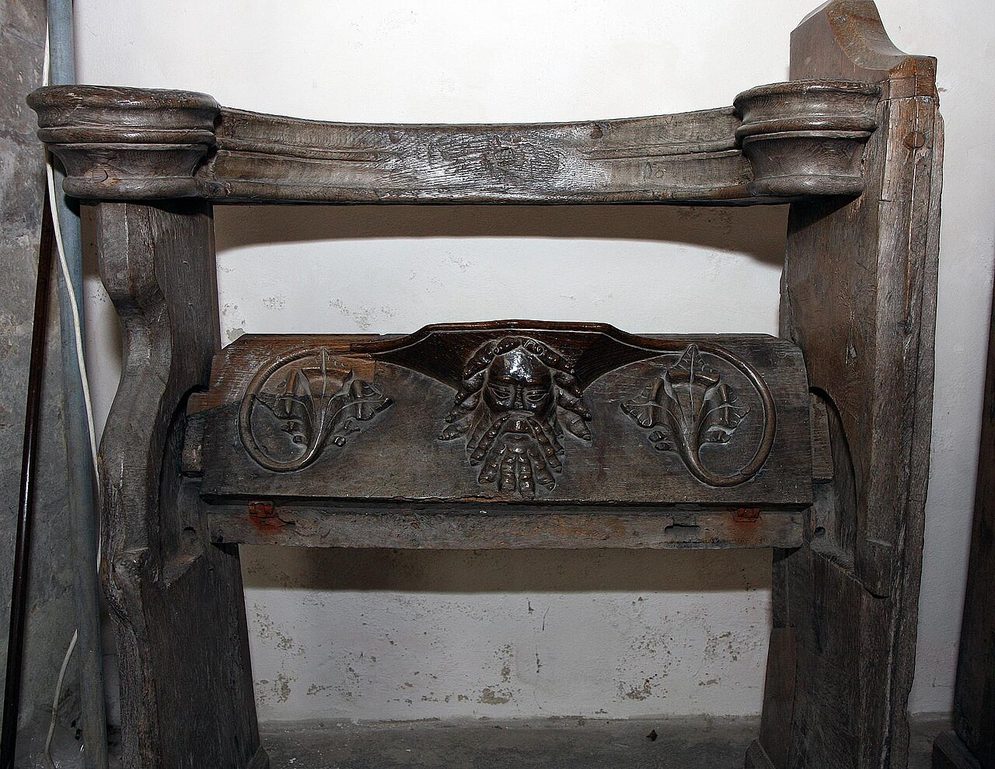A carved wooden misericord seat at Binham Priory with a bearded face in foliage