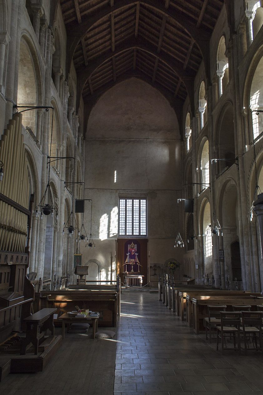 The tall Norman nave of Binham Priory, round arches in three tiers rising to a timber roof, looking west