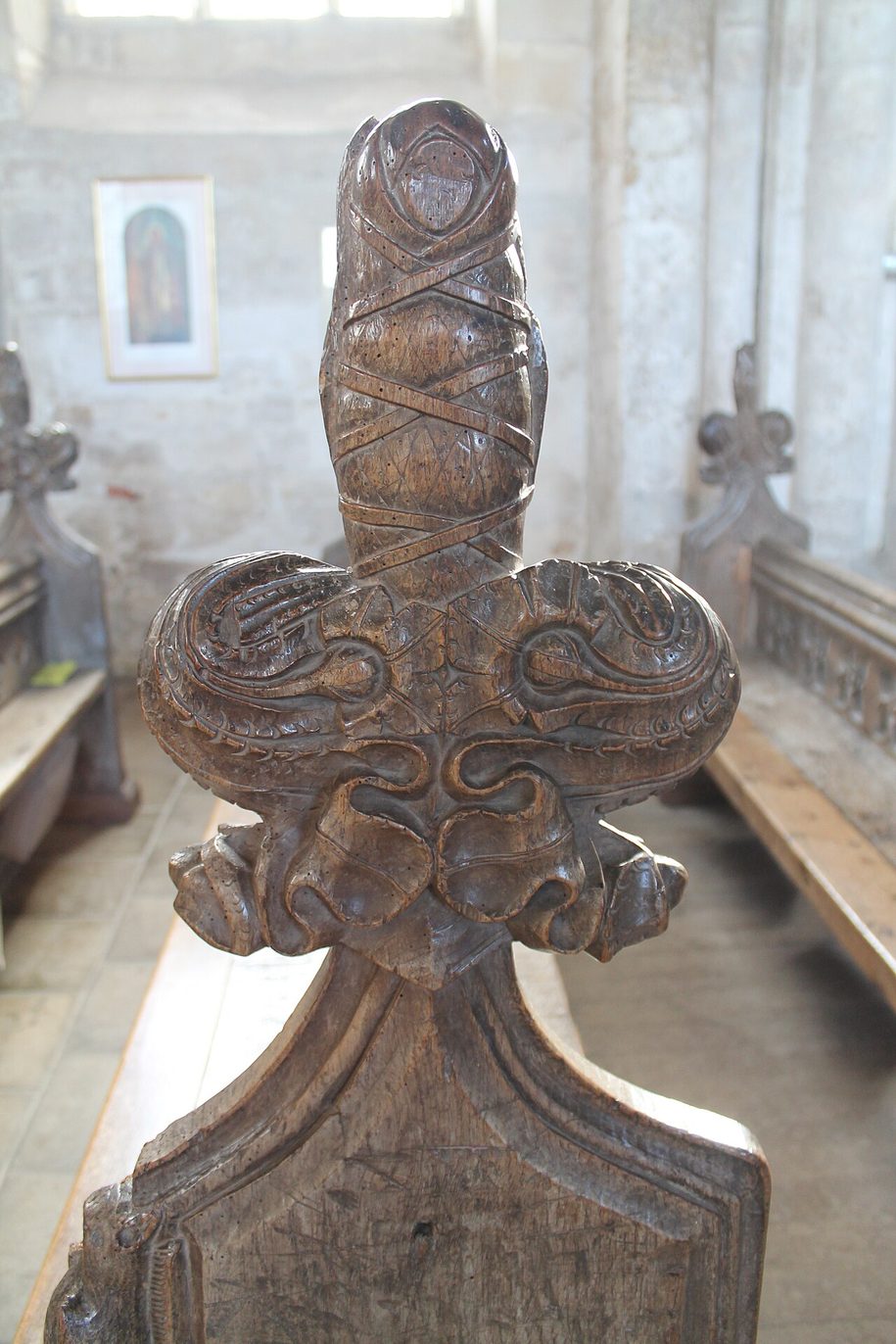 A carved wooden bench end at Binham Priory topped by a figure of a swaddled baby