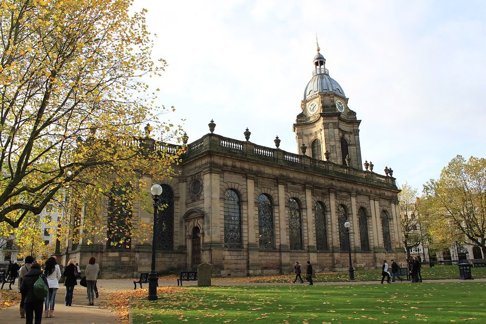 Birmingham Cathedral, a pale stone baroque church with a domed tower, standing on the lawns of its churchyard