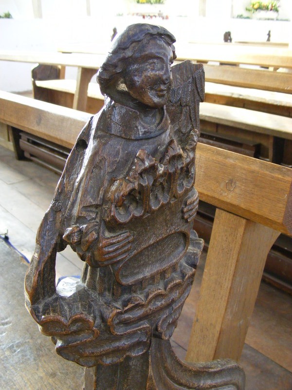 A carved medieval bench end at Blythburgh church showing a figure