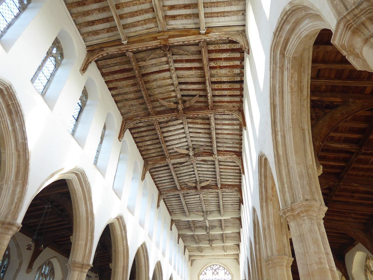 The light-filled nave of Holy Trinity Blythburgh with clear glass windows and a brick floor