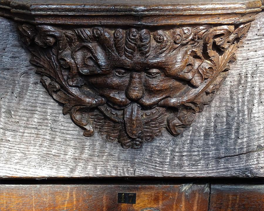 A carved wooden misericord with a grotesque face among foliage