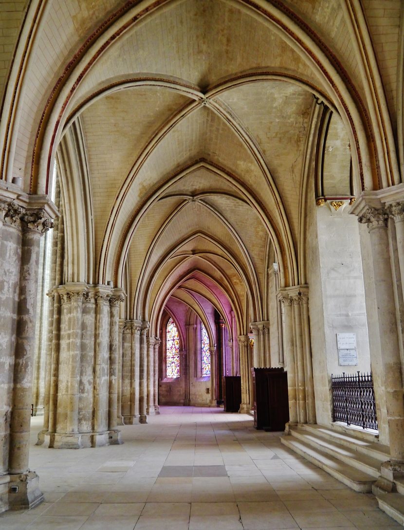 The vaulted double ambulatory of Bourges Cathedral curving round the choir, with stained glass at the end