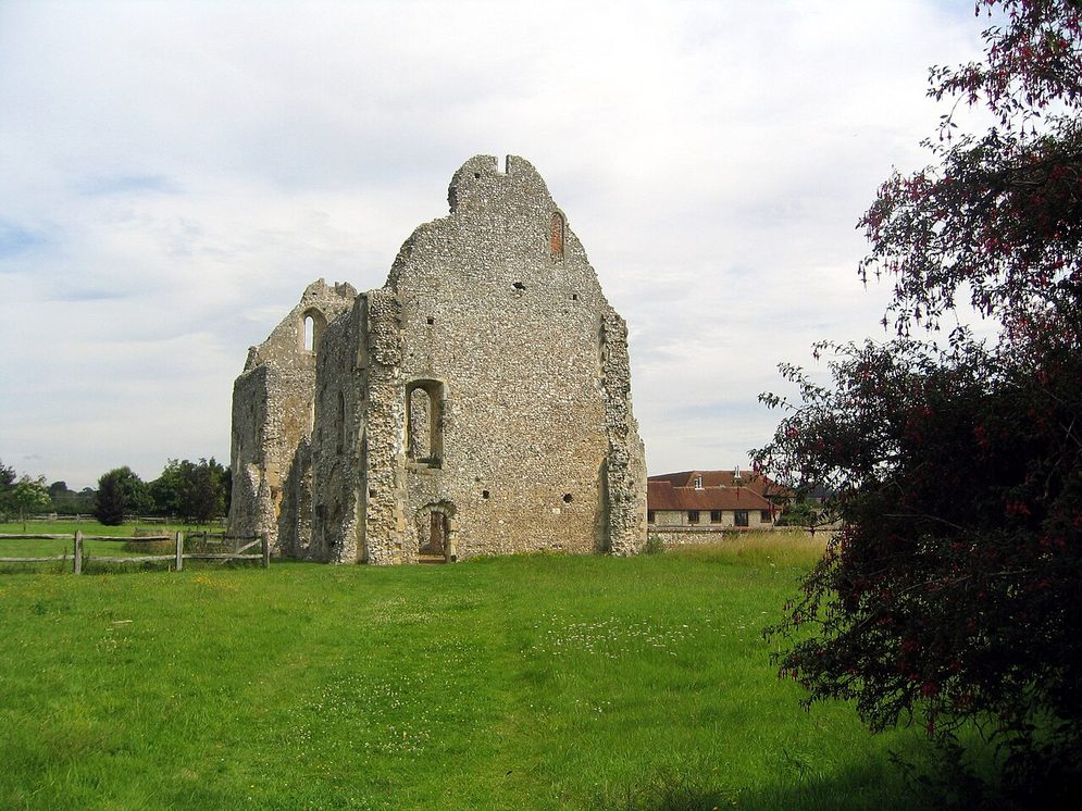 The roofless flint walls of the fourteenth-century guest house of Boxgrove Priory in a field