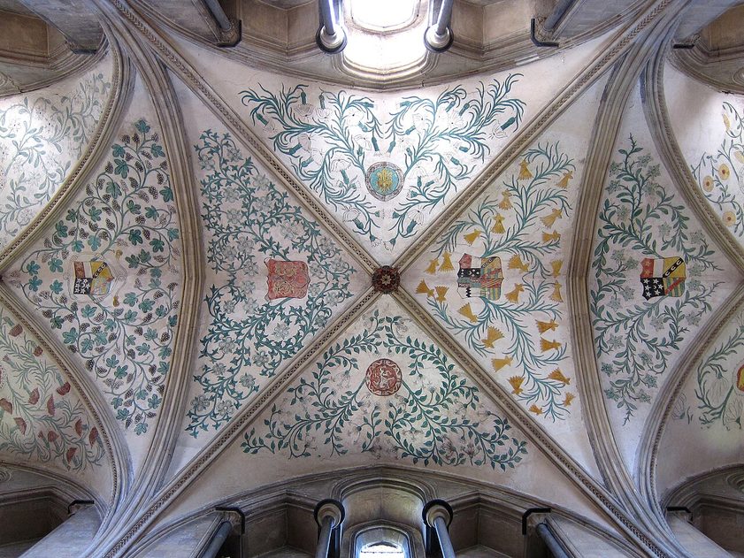 The painted vault of Boxgrove Priory, with flowers, foliage and coats of arms between the stone ribs