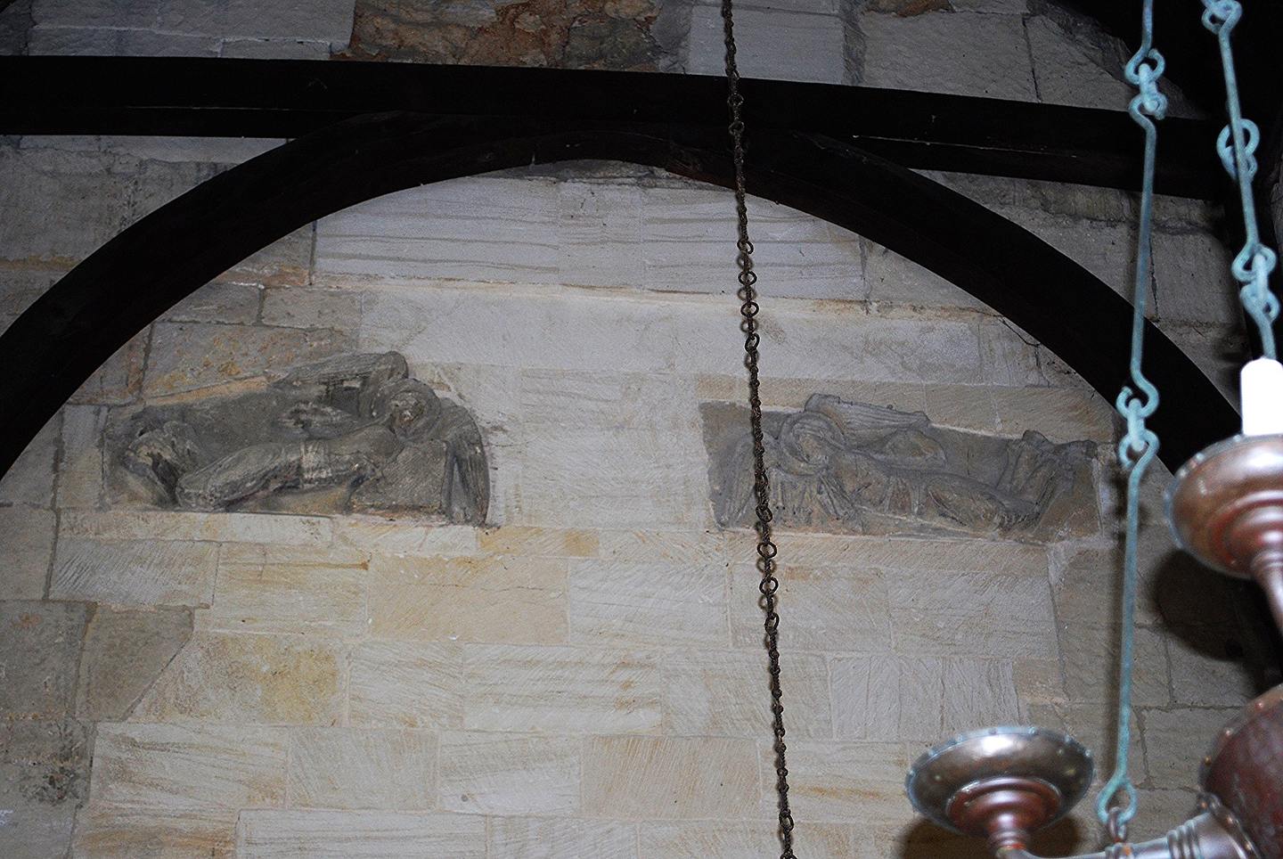 Two Anglo-Saxon carved stone angels flying horizontally, set high in the wall above the chancel arch