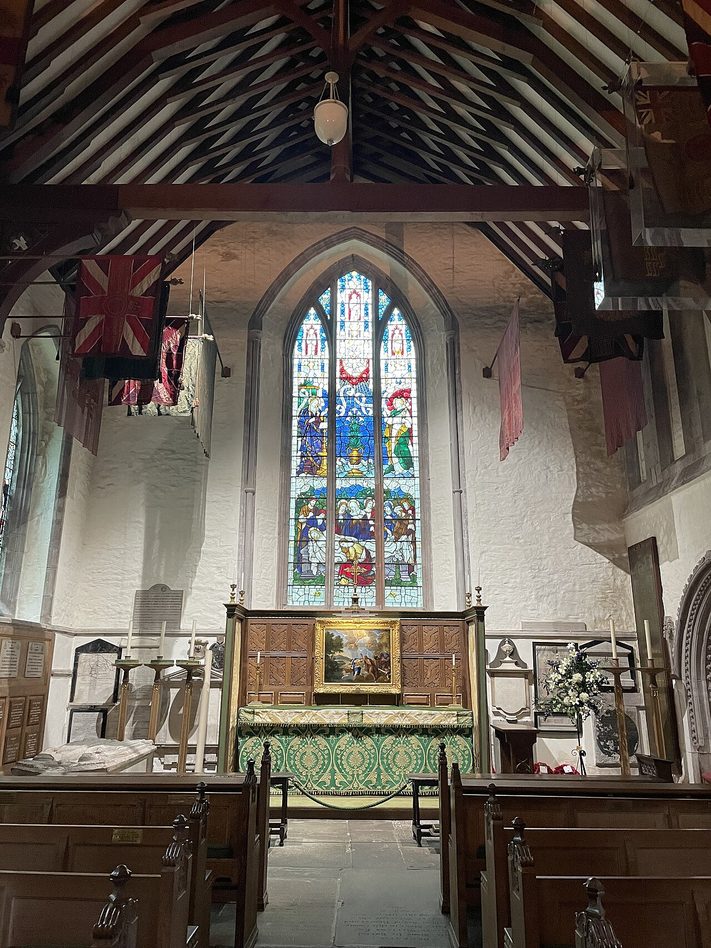 The Havard Chapel at Brecon Cathedral, with regimental colours hanging above the altar and a stained-glass window behind