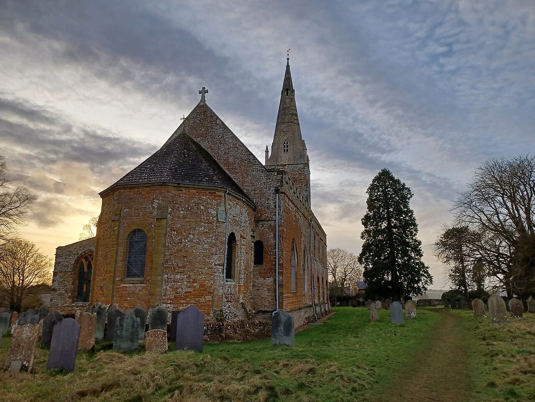 The outside of the east end of Brixworth church, with the curved wall of the apse and the sunken passage around it