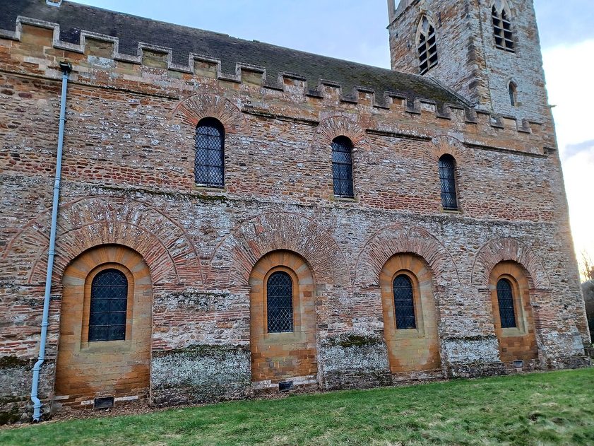 Round arches outlined in reused Roman brick tiles in the wall of Brixworth church