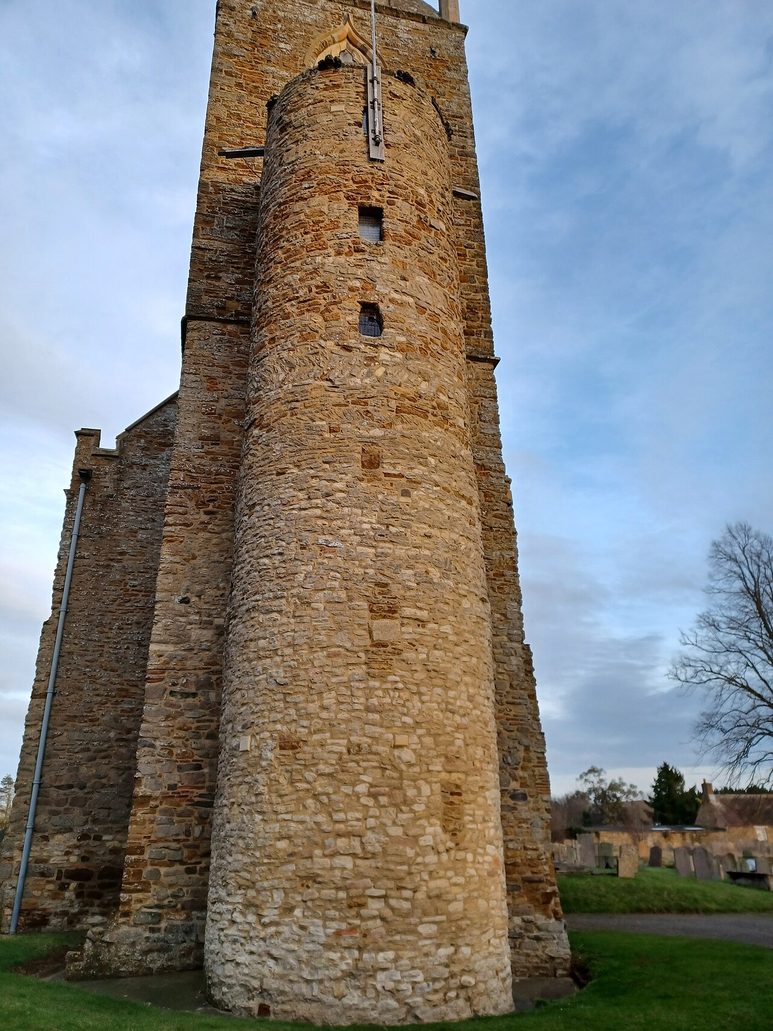The west tower of Brixworth church with its rounded stair turret and stone broach spire