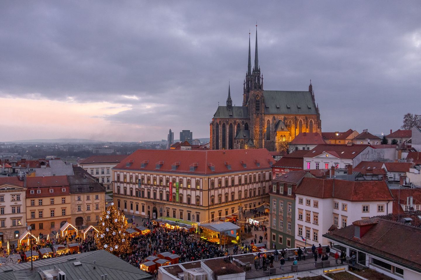 Brno cathedral lit up at dusk above the Christmas market on Cabbage Market square