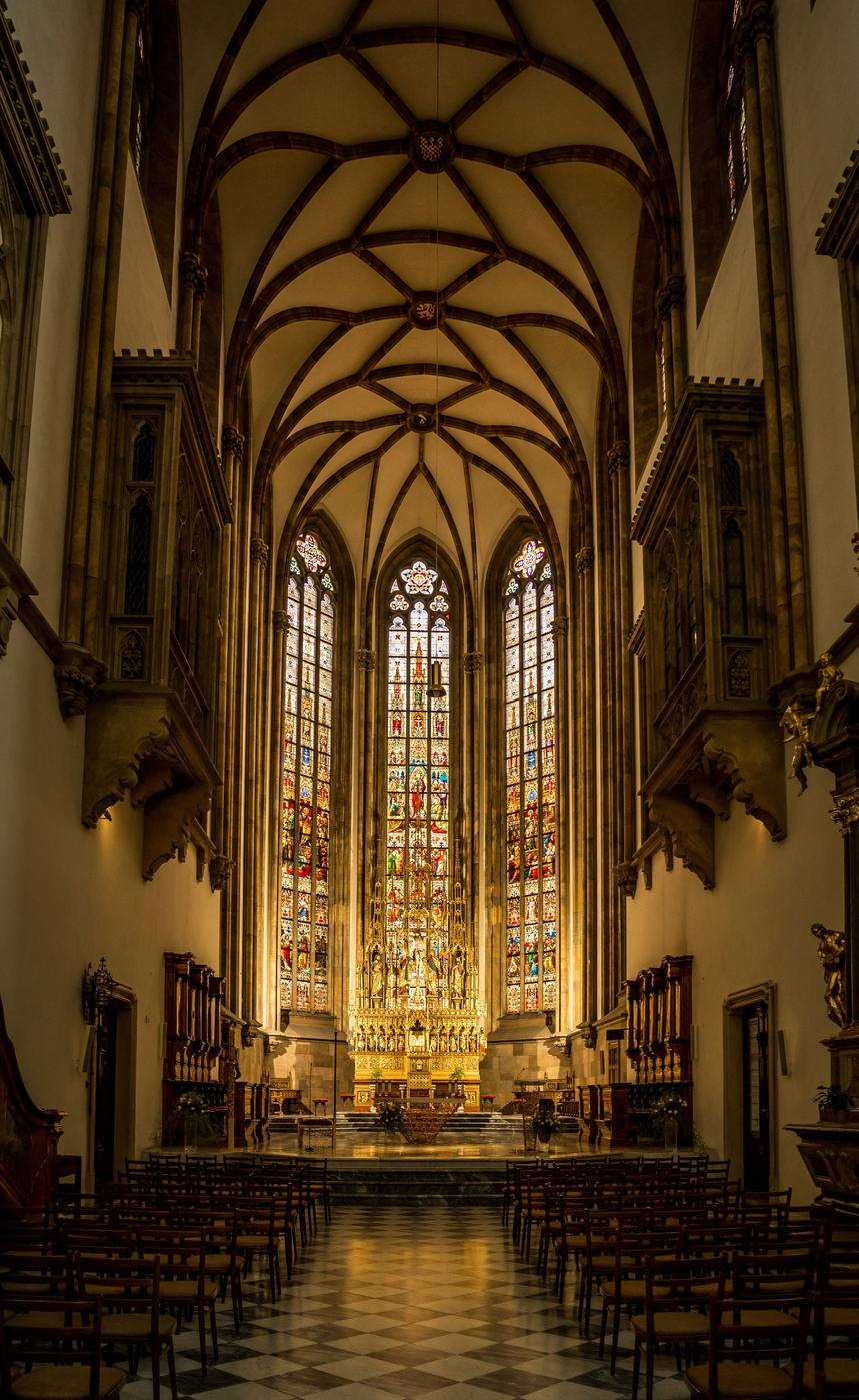 The richly lit Gothic choir of Brno cathedral with stained glass and gilded altar