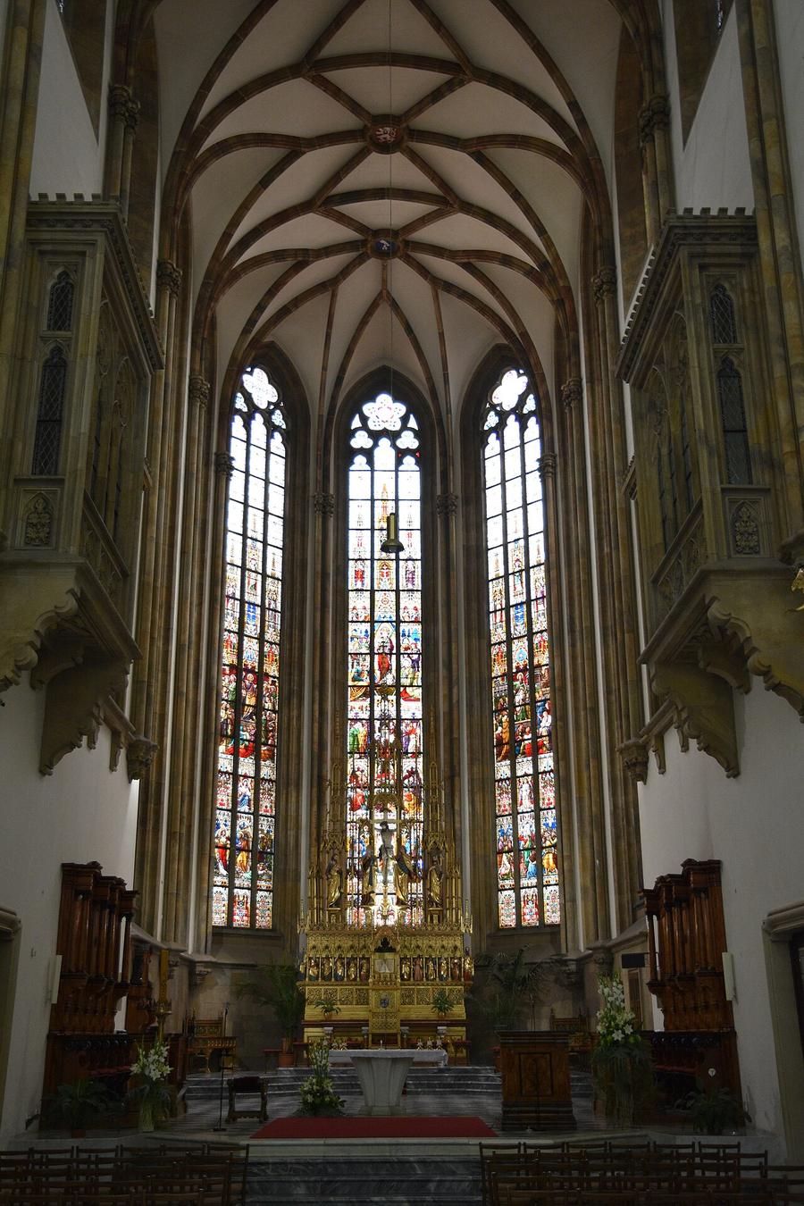The Gothic choir of Brno cathedral with tall stained-glass windows behind the high altar
