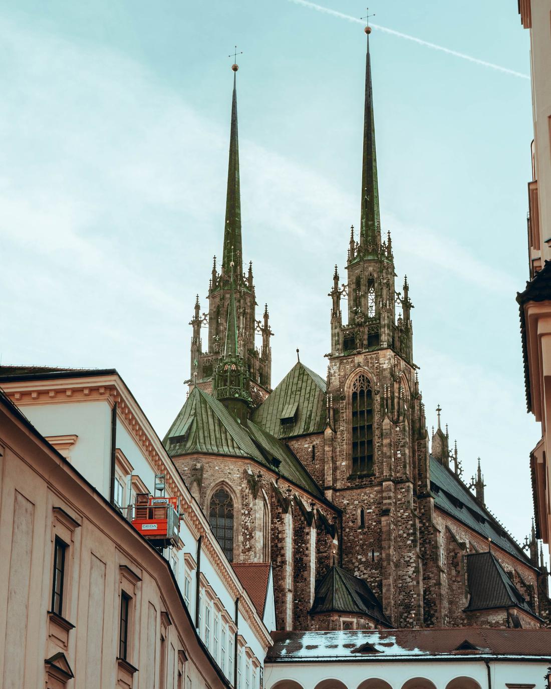 The spires of Brno cathedral seen at the end of a street of old buildings