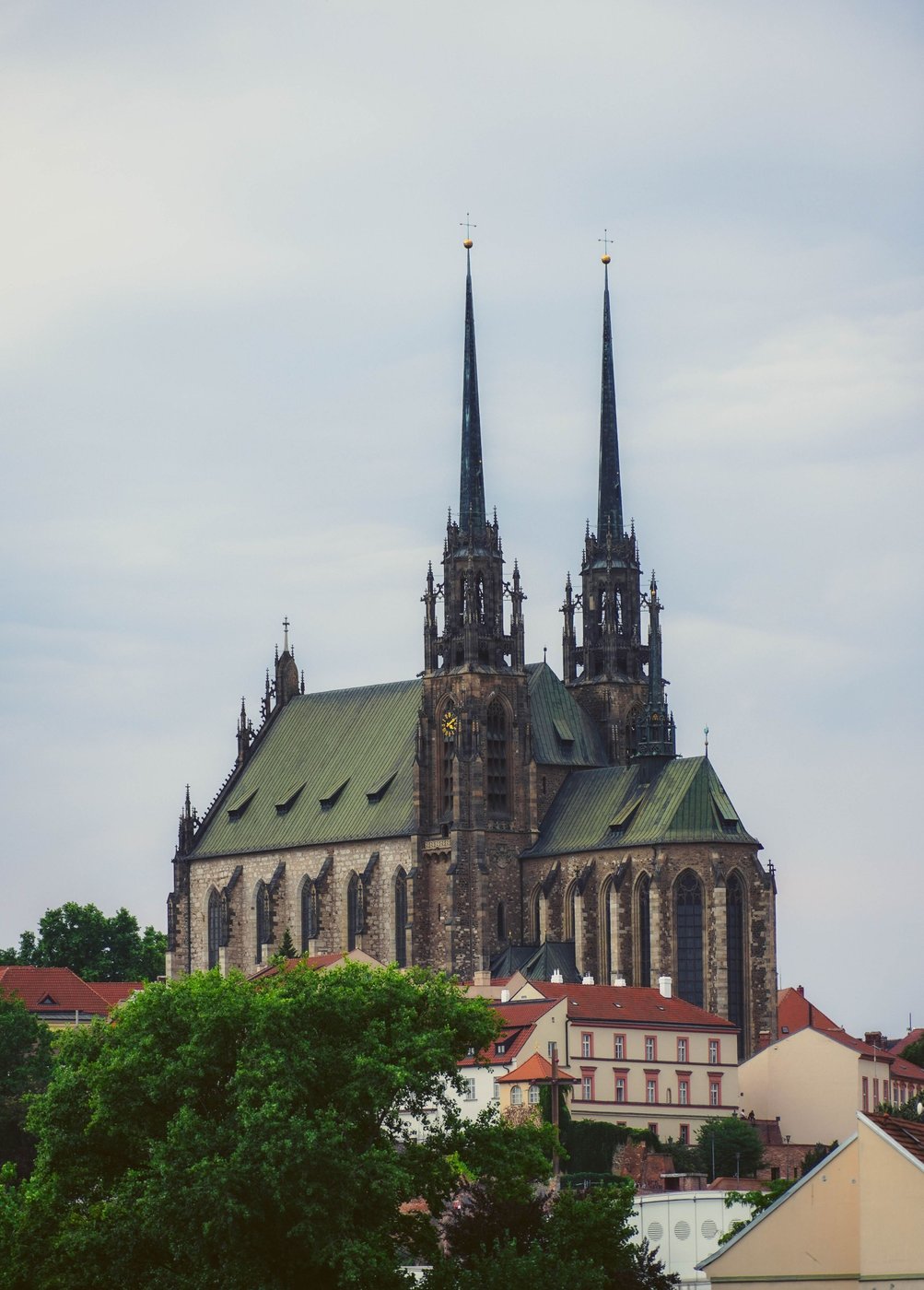 The two neo-Gothic spires of Brno cathedral on the Petrov hill above trees and houses