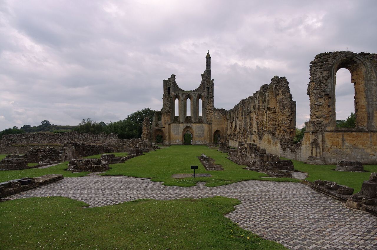 The ruined walls and arches of Byland Abbey on a grassy site