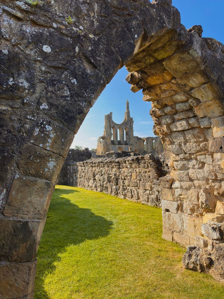 The west front of Byland Abbey seen through a ruined stone archway