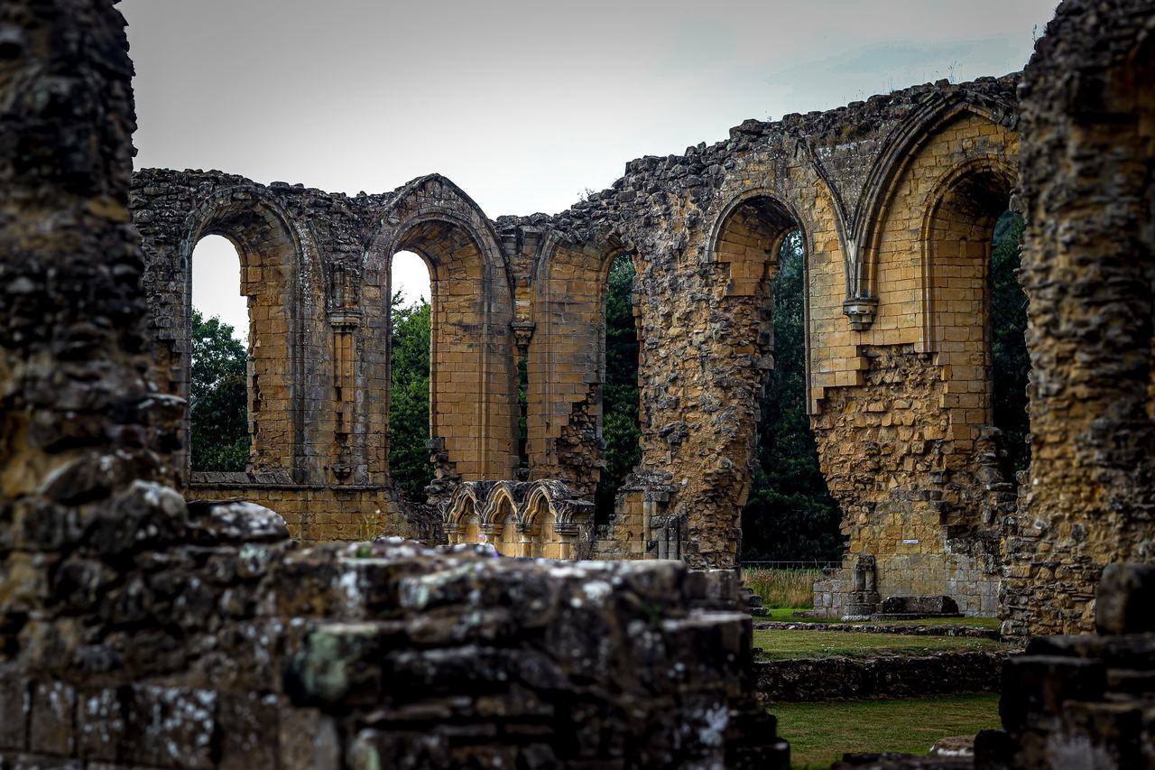 The ruined arches of the church of Byland Abbey, with trees behind