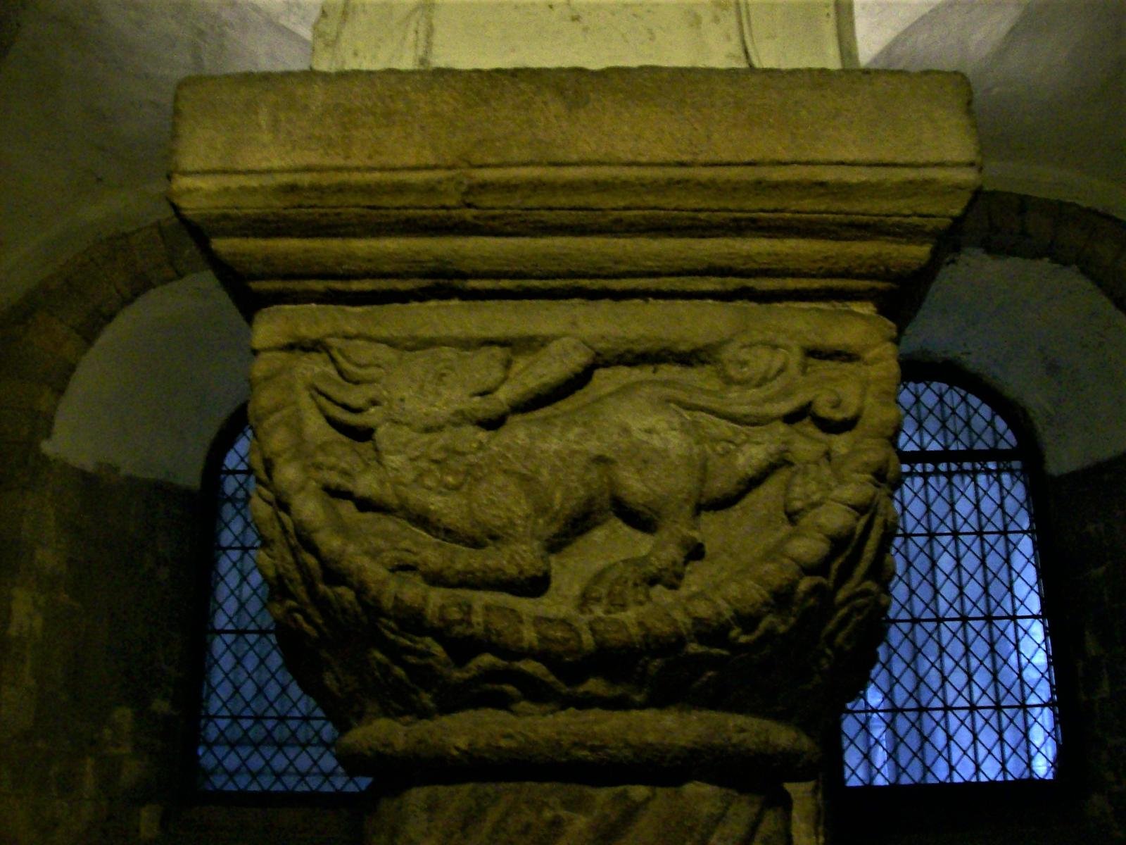 A carved Romanesque capital in the crypt of Canterbury Cathedral, showing a beast