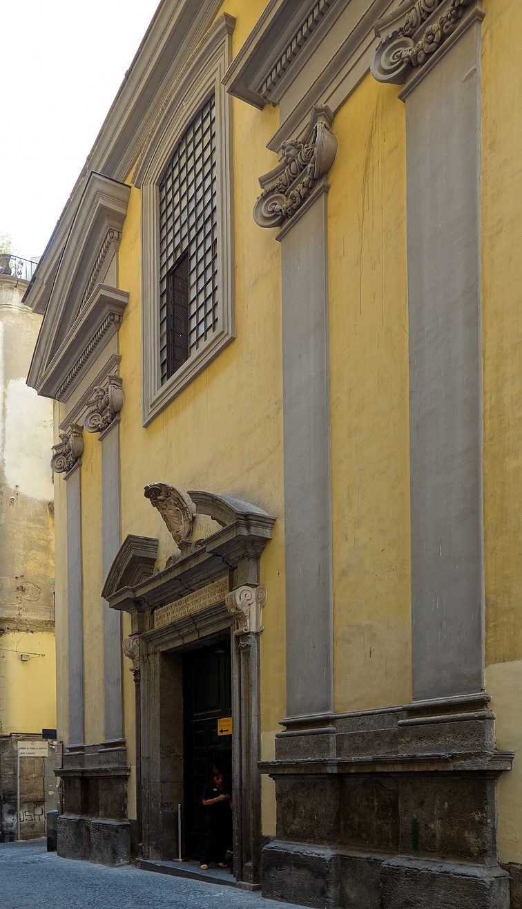 The plain yellow and grey street front of the Cappella Sansevero in a narrow lane of Naples' historic centre