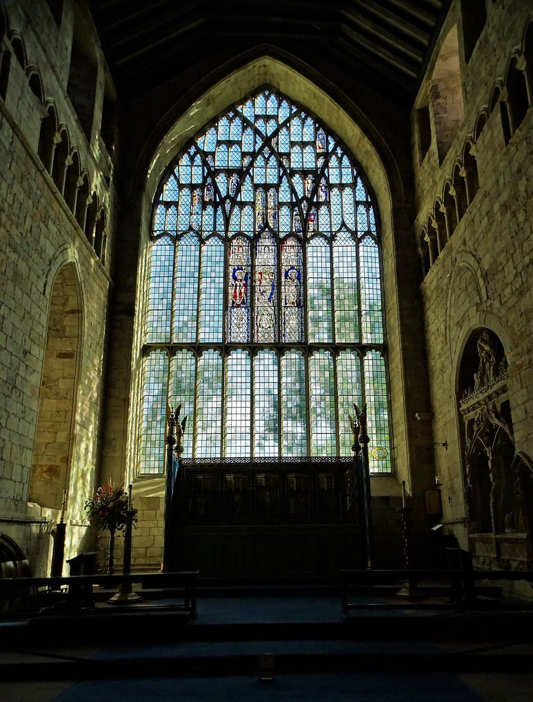The great east window of Cartmel Priory seen from inside the chancel, filling almost the whole east wall