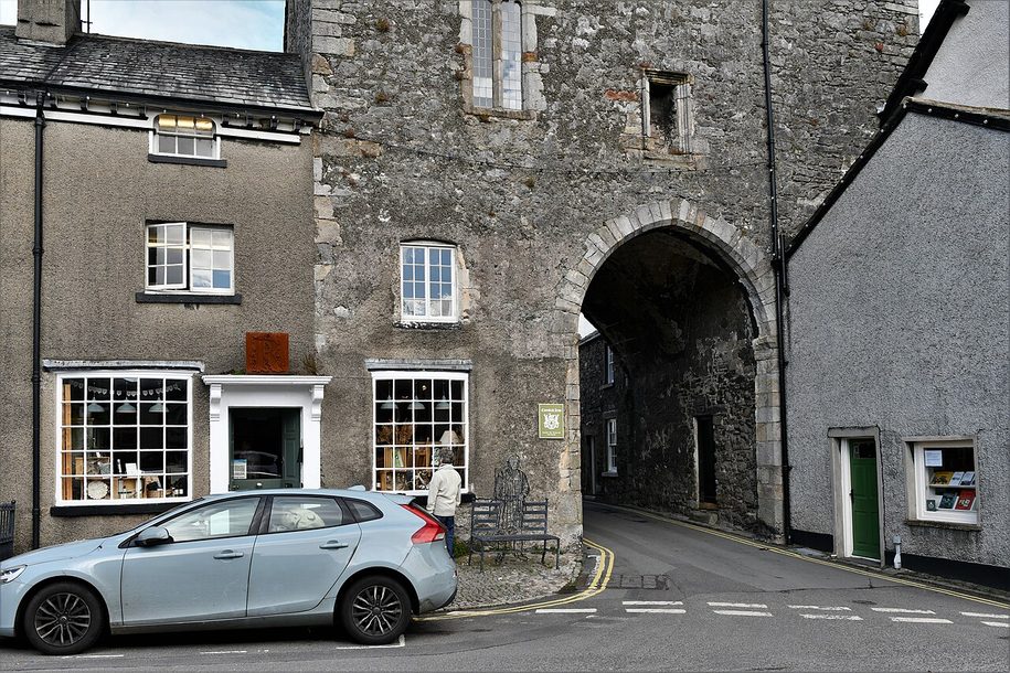 The stone gatehouse of Cartmel Priory with its archway over the street in the village square