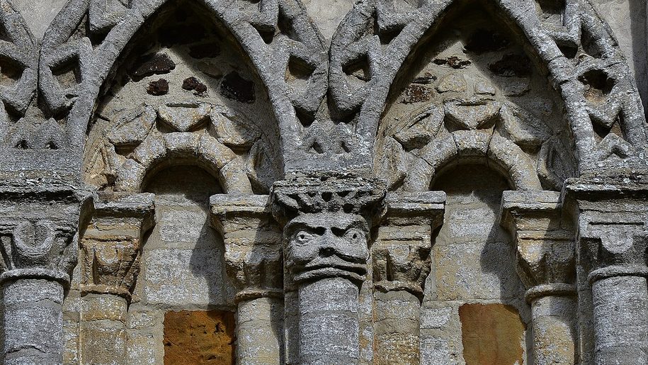 Detail of the interlaced Norman arcading on the west front of Castle Rising church, carved with zigzag and heads