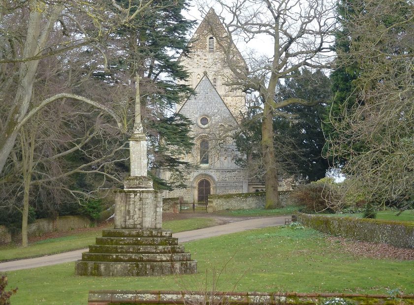The market cross on the green at Castle Rising, with trees and the village around it