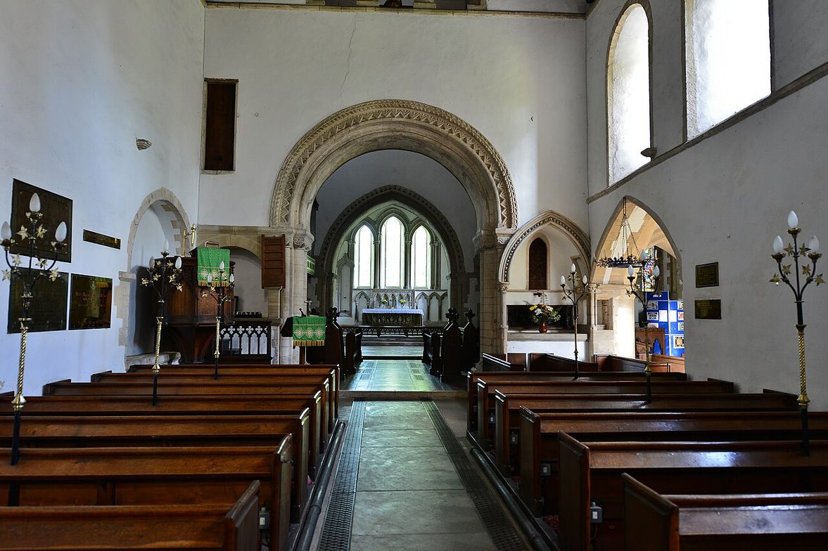 The nave of St Lawrence's Church, Castle Rising, looking east through two round Norman arches under the tower to the chancel