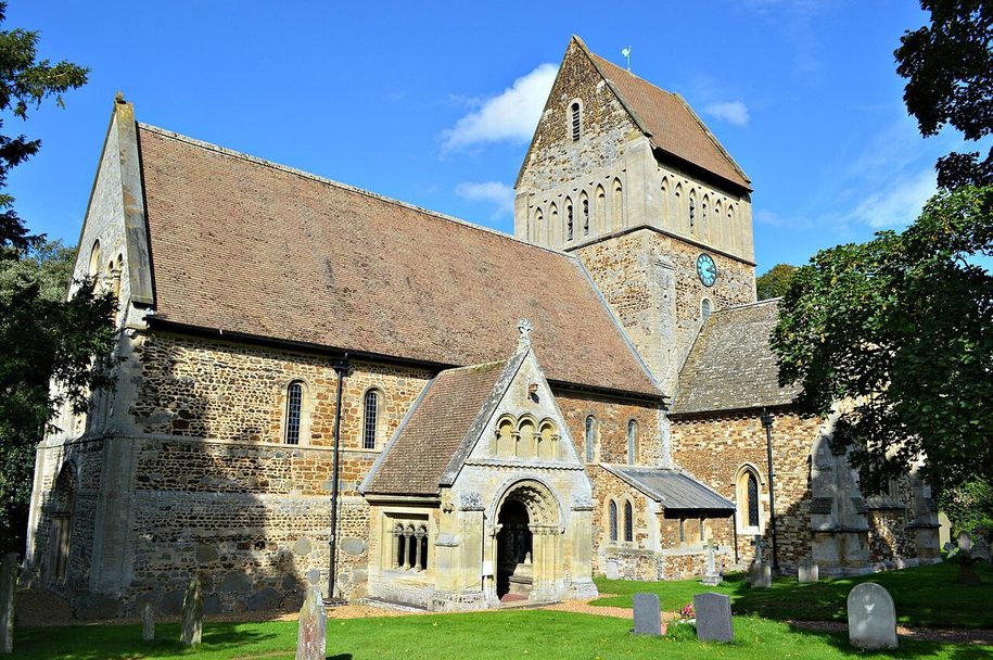 St Lawrence's Church, Castle Rising, from the south, with its saddleback-roofed central tower and Victorian porch among trees