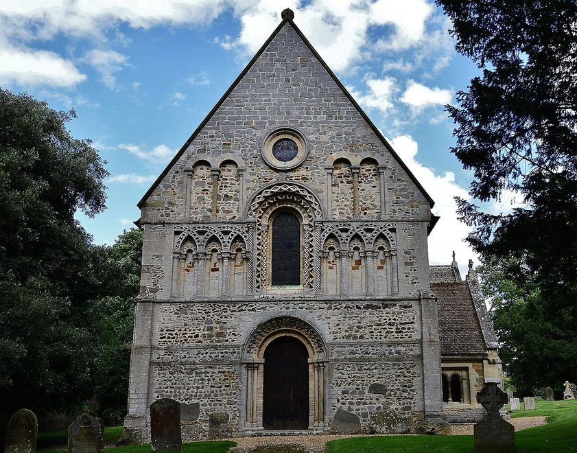 The Norman west front of St Lawrence's Church, Castle Rising, with a carved round-arched doorway, window and arcading under a stone gable