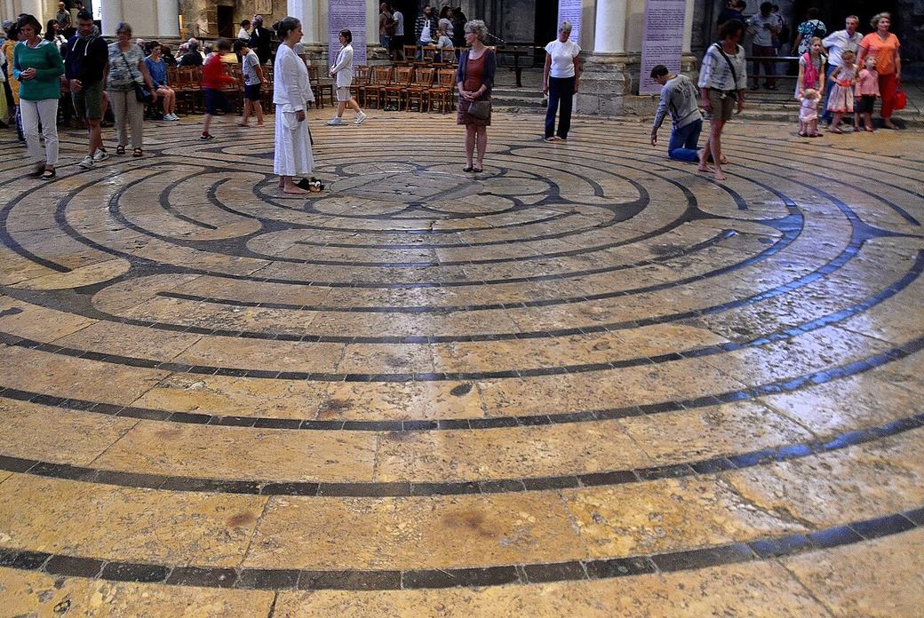 The circular stone labyrinth set in the floor of the nave at Chartres, with visitors walking it