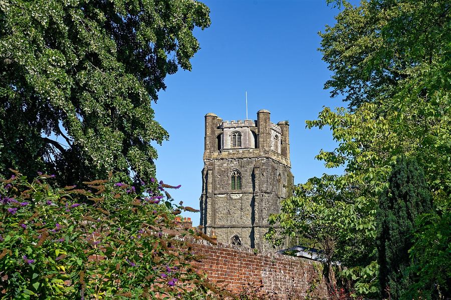 The detached medieval bell tower of Chichester Cathedral among trees
