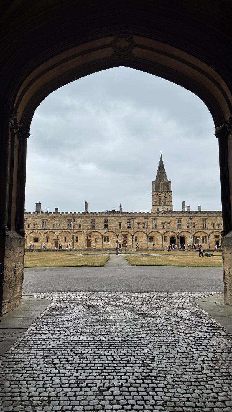 Tom Quad at Christ Church seen through a stone archway, with the cathedral spire beyond