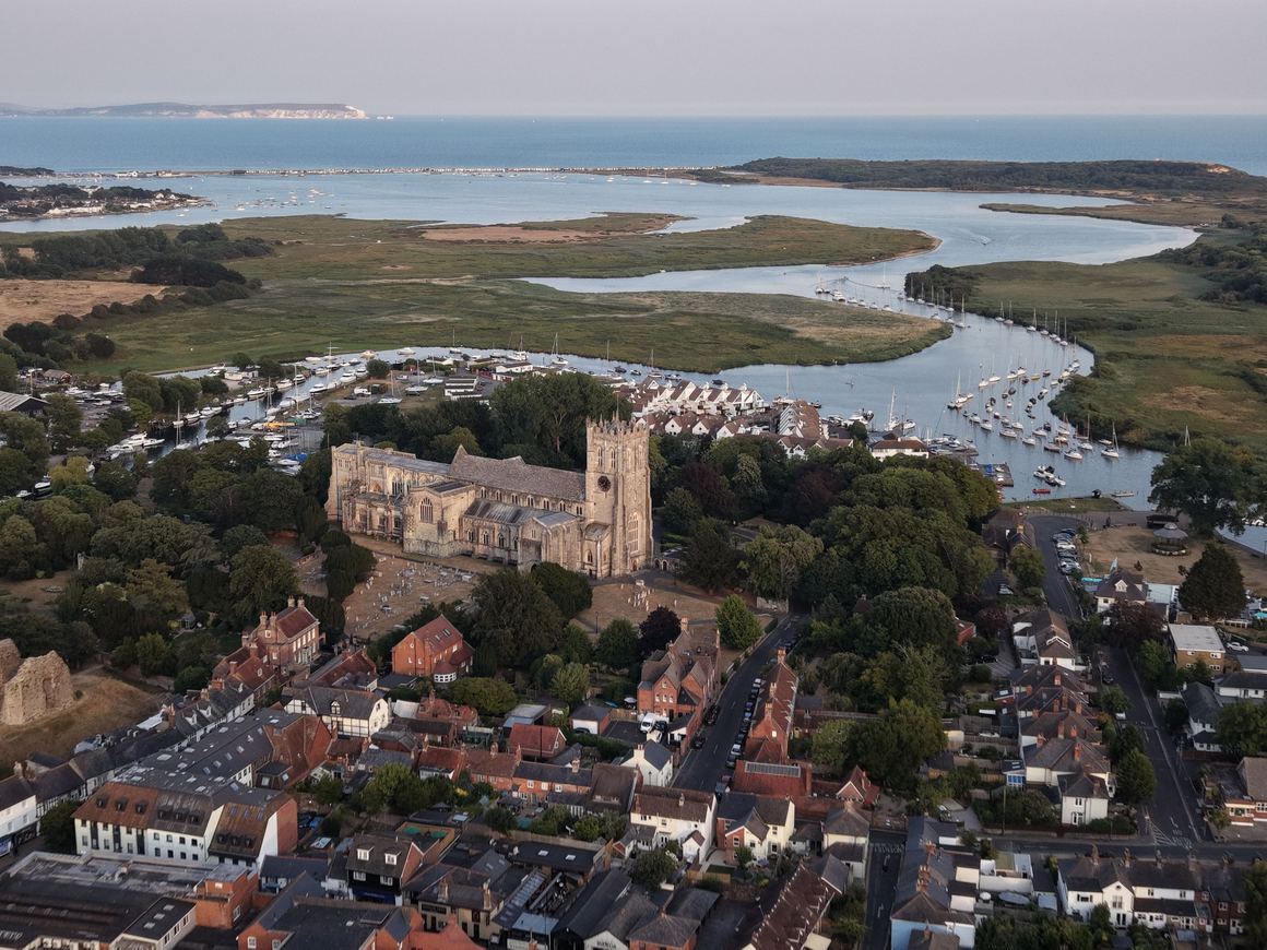 Aerial view of Christchurch Priory with the harbour and the sea beyond