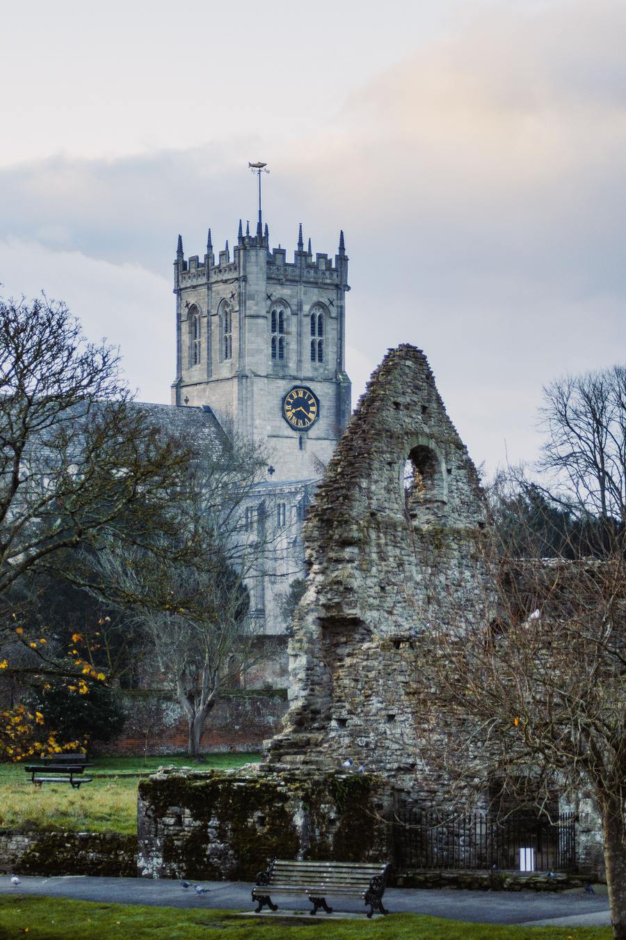 The ruined Norman Constable's House beside the River Avon with the Priory tower behind